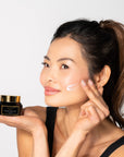 Woman applying cream to face with A jar of Bella Vida Santa Barbara Brighten Vitamin C Cream with two Beauty Shortlist 2025 and 2024 Award Winner 
