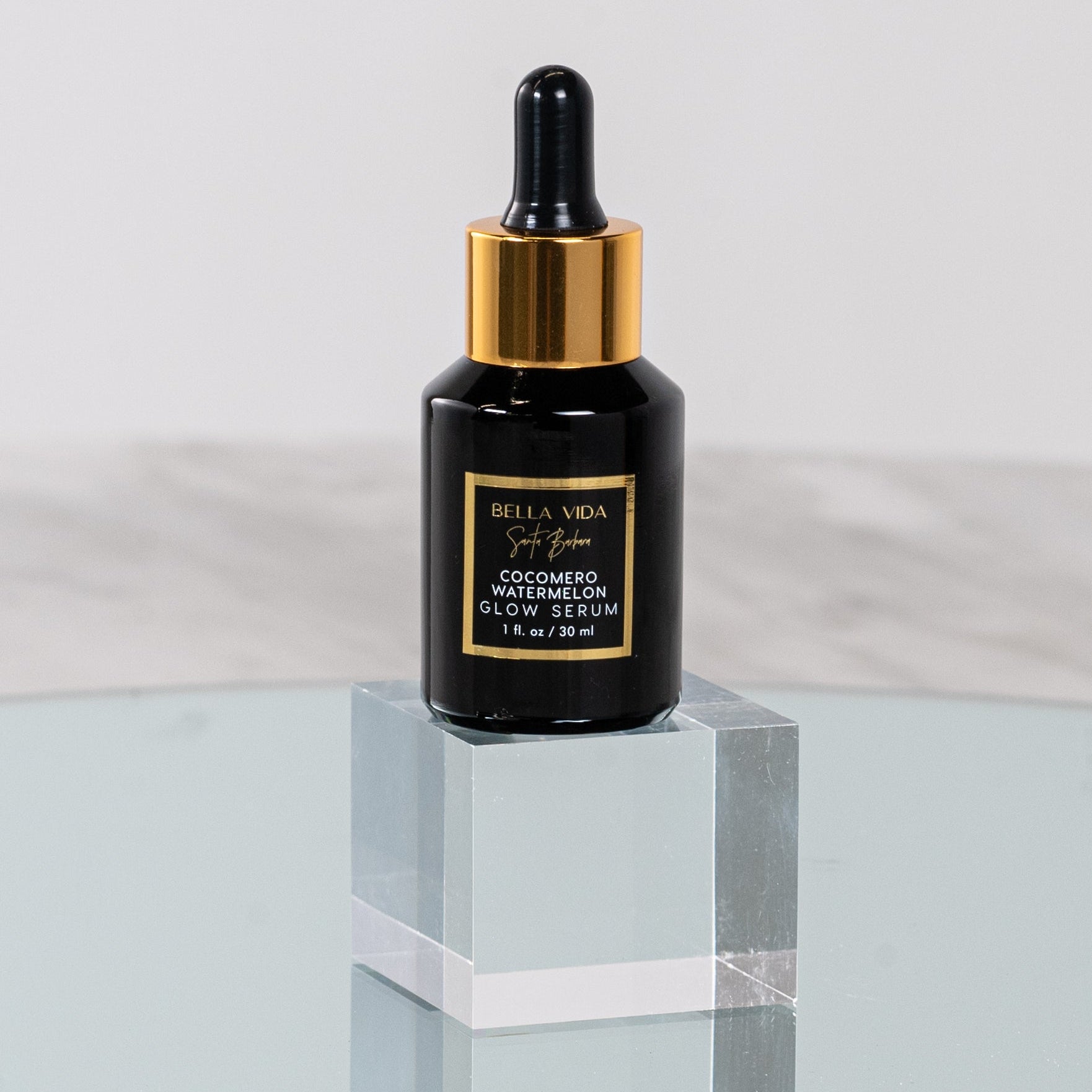 A black bottle with a dropper of Cocomero Watermelon Glow Serum with Hyaluronic Acid, labeled with the brand Bella Vida Santa Barbara luxury skincare, and an award badge for 'Beauty Shortlist Editor's Choice 2024'. The product is described as helping to achieve a glow and radiance for the skin.